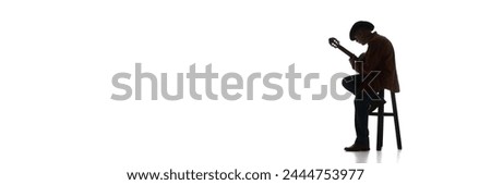 Man in fedora hat sitting on chair and playing guitar on white background. Black and white image. Concept of music, festival, concert, entertainment, instruments. Banner, empty space for ad