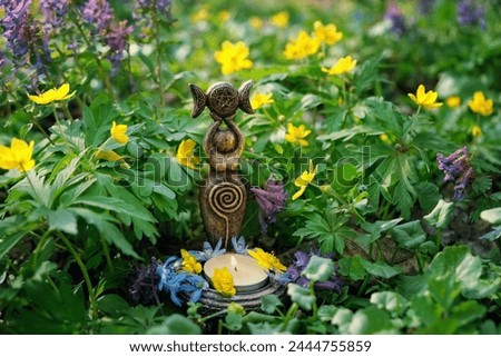 amulet of Triple Goddess with candle close up on floral meadow, natural background. Symbol of the Triune Moon. esoteric ritual for Beltane. witch, wiccan spiritual practice for relax, harmony Royalty-Free Stock Photo #2444755859