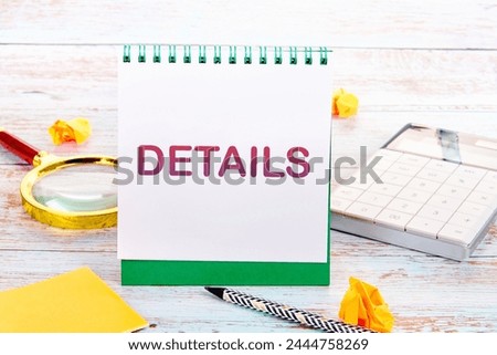 Business concept. DETAILS word on a white notebook on a wooden plank floor next to a calculator, crumpled stickers, a magnifying glass and a pencil