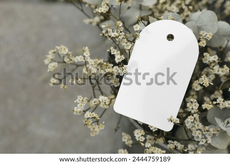 Floral wedding, birthday mockup. Empty paper gift tag, label. Limonium flowers and eucalyptus tree branches bouquet in metal bucket. Blurred background. Sale. Floristry branding concept