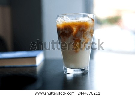 A large transparent glass filled with cold summer drink with ice cubes is photographed on a gray, isolated background, photo for the menu . High quality