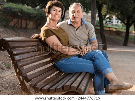 elderly man and woman embracing on bench Royalty-Free Stock Photo #2444776919