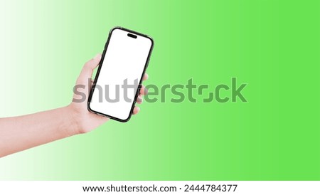 Close-up of hand holding smartphone with blank on screen isolated on background of green.