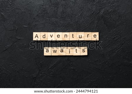Adventure awaits word written on wood block. Adventure awaits text on cement table for your desing, concept.