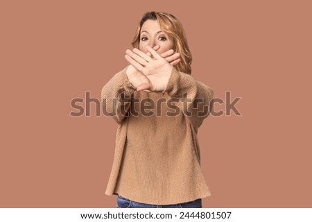 Blonde middle-aged Caucasian woman in studio doing a denial gesture
