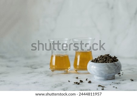 Leaf tea in a marble bowl and two glass Turkish cups with tea
