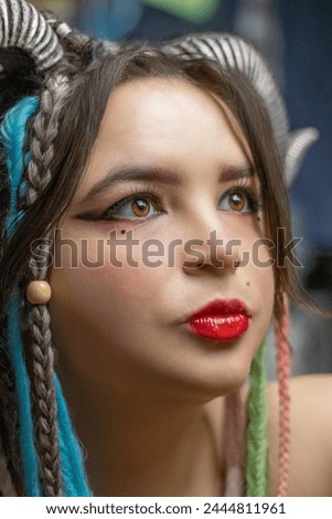 The girl with the horns looks past the camera. Close-up portrait