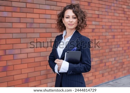 Portrait of a successful business woman in front of modern business building. Young manager poses outside. Female business leader