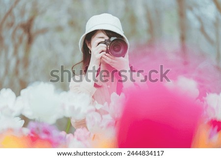 A woman takes pictures of colorful tulips blooming in a tulip field in Saitama