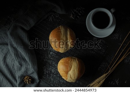 Sweet bread filled with meat with cheese on the outside, on cooling tray with A cup of tea. Dark background