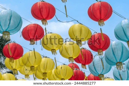 Picture a row of colourful Chinese paper lanterns hanging with a blue sky background. Festive picture with no people