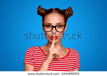 Portrait of attractive mysterious girl in glasses gesturing silence sign with forefinger red pout lips looking at camera isolated on red background Royalty-Free Stock Photo #2444898905