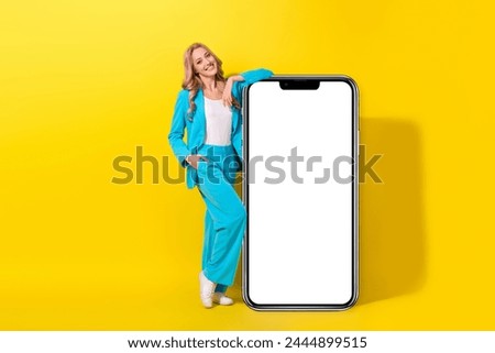 Full size photo of lovely girl dressed blue jacket trousers lay hand on smartphone display empty space isolated on vivid yellow background