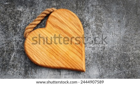Wooden cutting board in the shape of a heart on a gray background .