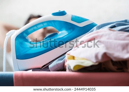 Close up photo of man holding flat iron and ironing clothes. Male household concept	