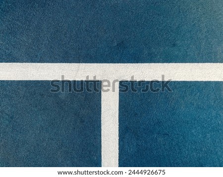Racquet or Paddle Sports Court Surface Close-Up. Vibrant colored sport or tennis court surface. Close-up views of the white boundary lines against a blue surface. Serving line and center line depicted Royalty-Free Stock Photo #2444926675