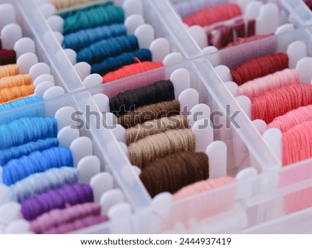 Plastic sorting box full of bobbins with different color embroidery threads. Close-up Royalty-Free Stock Photo #2444937419