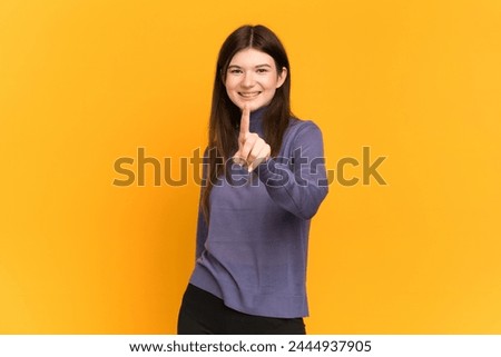 Young Ukrainian girl isolated on yellow background showing and lifting a finger