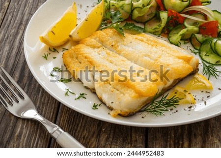 Seared halibut fillet and fresh vegetables on wooden table 