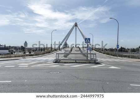 Image of the metal structure of a small bridge for road traffic and pedestrians, with signage indicative of road traffic vertically and horizontally on the pavement