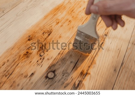 Oil and varnish for wood.mans hand paints wooden boards with oil. Impregnation of a wood with protective oil. Impregnation of wood with oil.Protecting the wooden surface from damage. Royalty-Free Stock Photo #2445003655