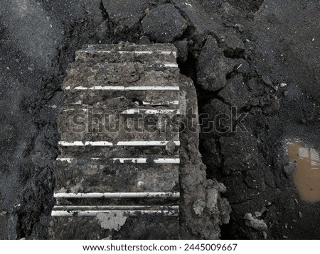 Photo of excavator track on dry coal sediment.