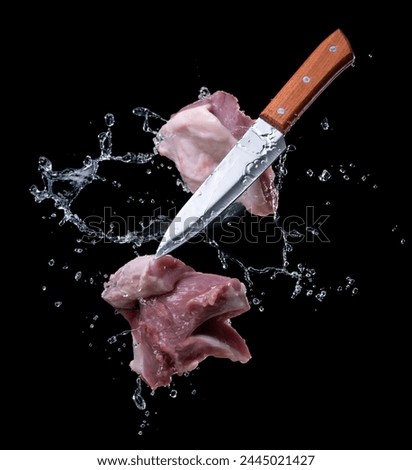 Flying pieces of pork with knife, isolated on black background Royalty-Free Stock Photo #2445021427