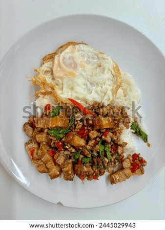 Thai dish call Pad kra pao. crispy pork and minced pork stir-fried with holy basil leaves, served with plain cooked rice and a fried egg.