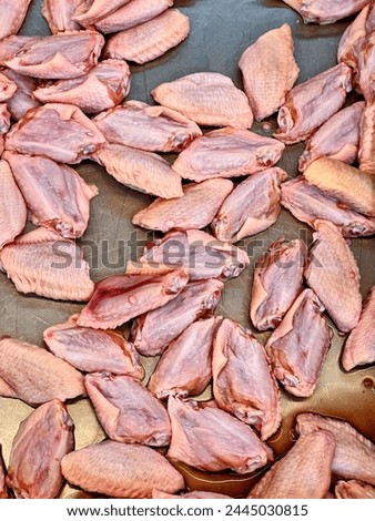 a photography of a bunch of raw chicken wings on a metal tray.
