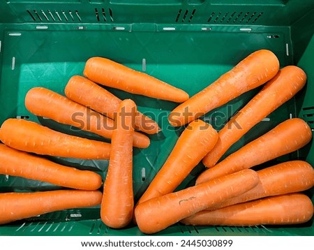 a photography of a green crate filled with carrots sitting on top of a table.