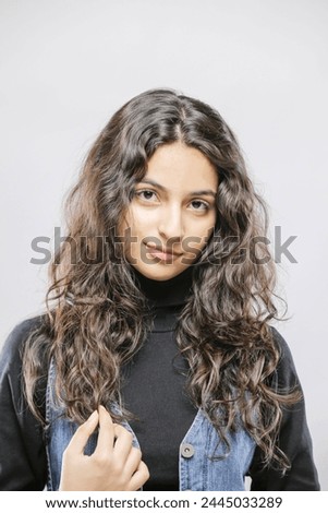 Pretty confident Pakistan female with fair hair, dressed casually, looking with satisfaction at camera, being happy. Studio shot of good-looking beautiful woman isolated against blank studio wall