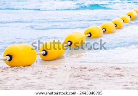 Yellow sea buoy. Ocean with floating buoys and rope dividers on the beach. Clear blue water and sandy beach. Sea background.