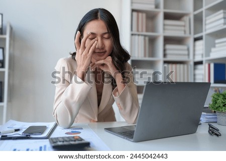 Asian businesswomen feel stressed at work when faced with hard work. Feeling headaches and eyestrain working on a laptop computer in the office.