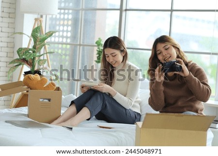 Two young Asian roommates prepared things in boxes, sat on their friend's bed, picked up a camera and took pictures before moving out of the rented apartment and moving to another place. Royalty-Free Stock Photo #2445048971