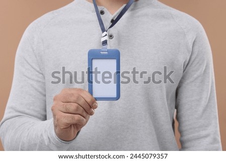 Man with blank badge on beige background, closeup