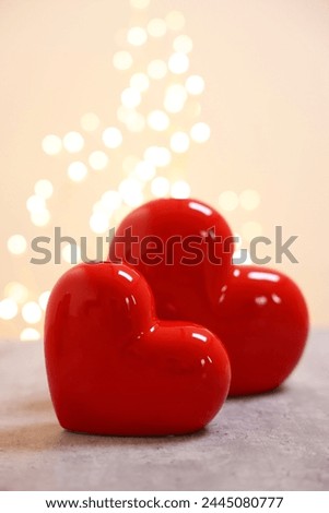 Red ceramic hearts on grey table against blurred lights