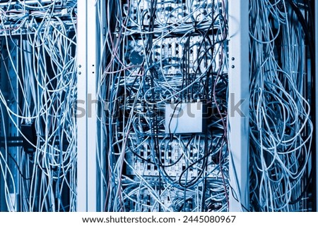 server room rack with tangled network cables creating messy untidy network system Royalty-Free Stock Photo #2445080967