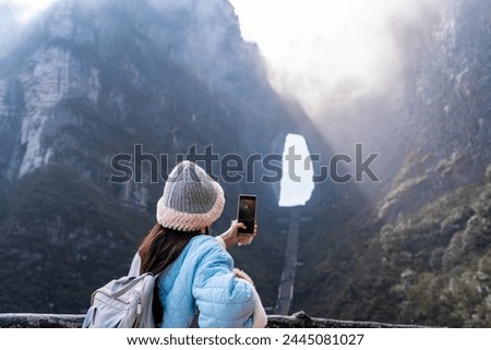 Young female tourist taking a photo of the The Heaven's Gate at Tianmen Shan national park, The famous tourist destination at Zhangjiajie