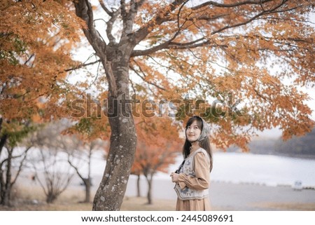 Asian woman in Japan's fall beauty, cheerful holiday portrait amid yellow and red foliage. A journey capturing the essence of nature, fashion, and casual elegance.