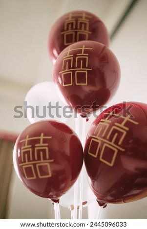 Glossy red balloons with golden Chinese characters symbolizing joy.