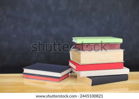 stack of books on wooden table against wooden wall. space for text, back to school concept
