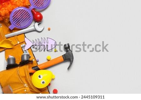 Belt with construction tools and party decor for April Fools Day celebration on grey background
