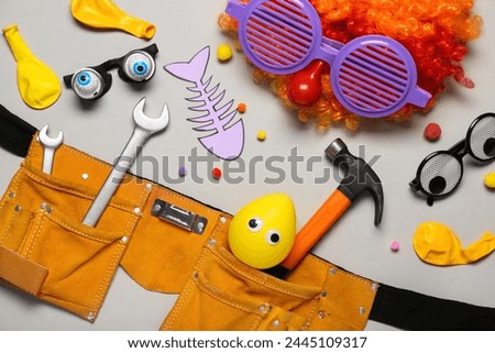 Belt with construction tools and party decor for April Fools Day celebration on grey background