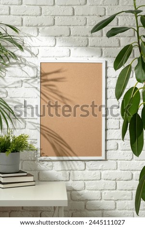 Shadow of Palm Leaves Cast on Framed Picture Against White Brick Wall