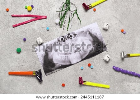 Composition with x-ray image of teeth and party decor on grunge background. April Fool's Day celebration