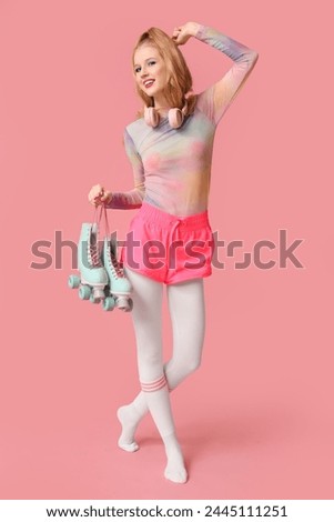 Beautiful young happy woman with vintage roller skates on pink background