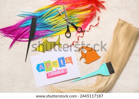 Card with text APRIL FOOL'S, hairdresser's supplies and party decor on light background