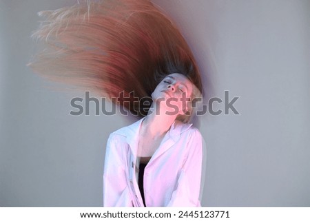 Fashionable portrait of beautiful young woman on grey background, long-exposure photography