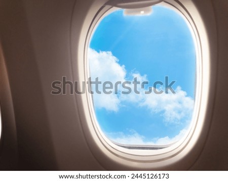 Fluffy clouds on a blue background in the porthole window Royalty-Free Stock Photo #2445126173