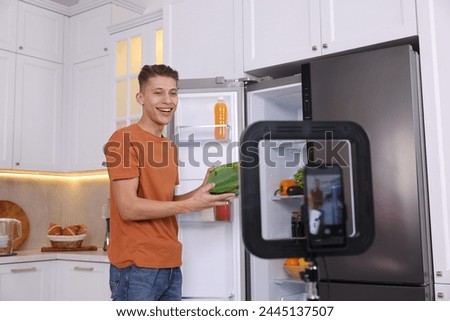 Smiling food blogger explaining something while recording video in kitchen Royalty-Free Stock Photo #2445137507